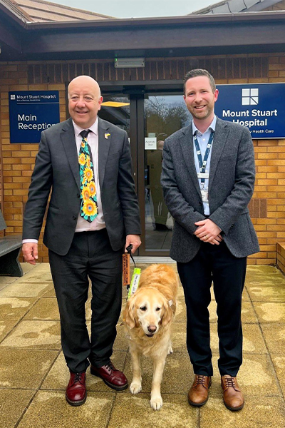 two men smiling with guide dog