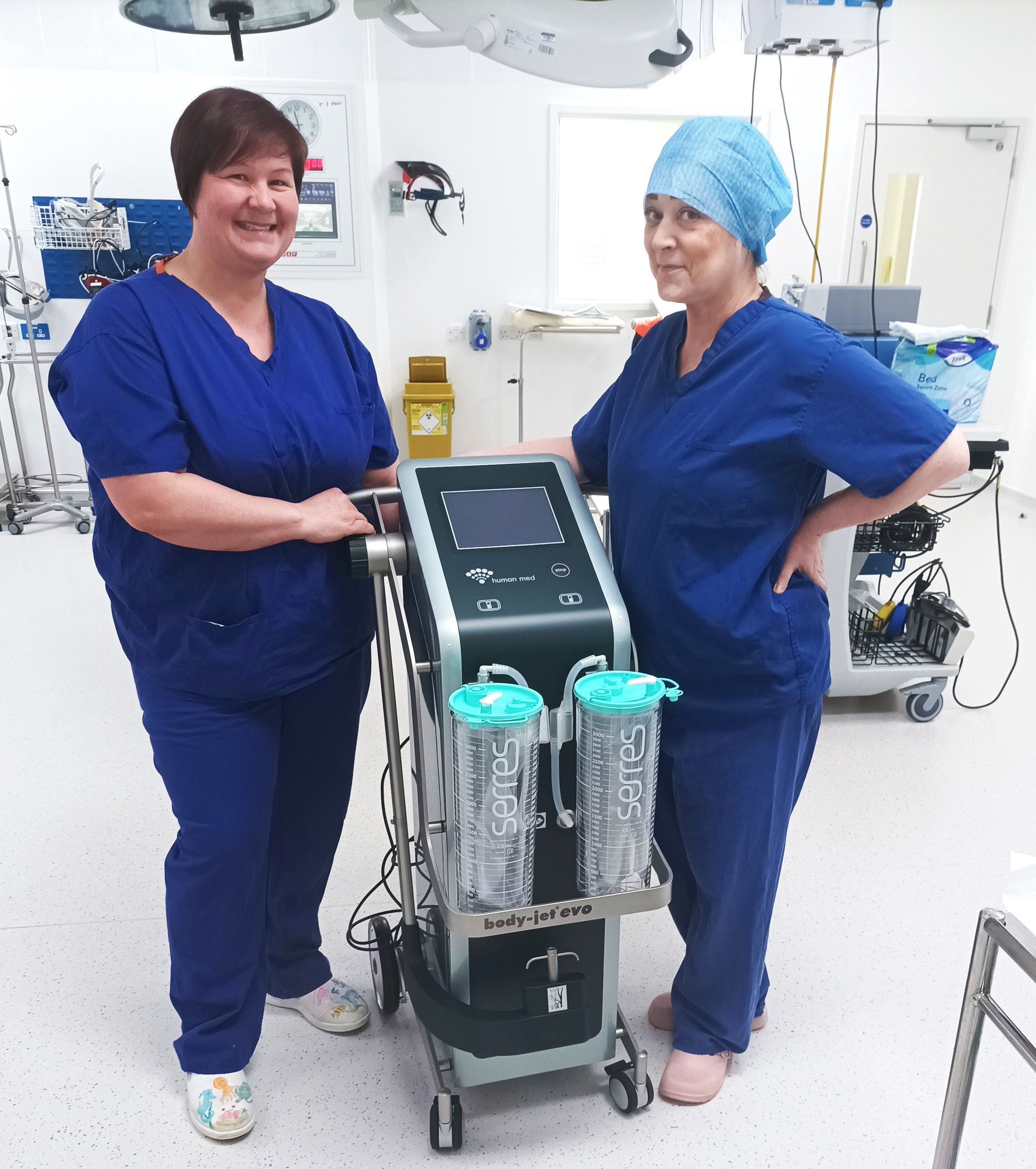 two medical staff stood in theatre with liposuction machine