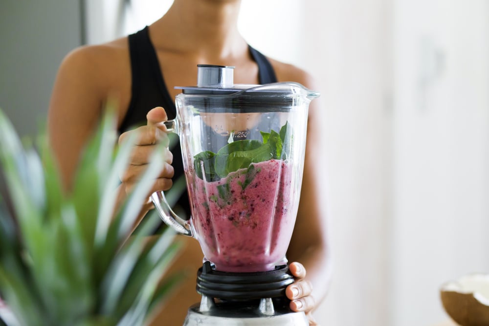 woman holding a blender with smoothie mix inside