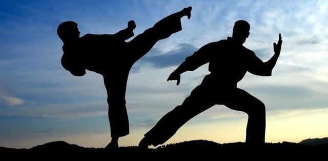 Two men in the shadows on a mountain doing karate