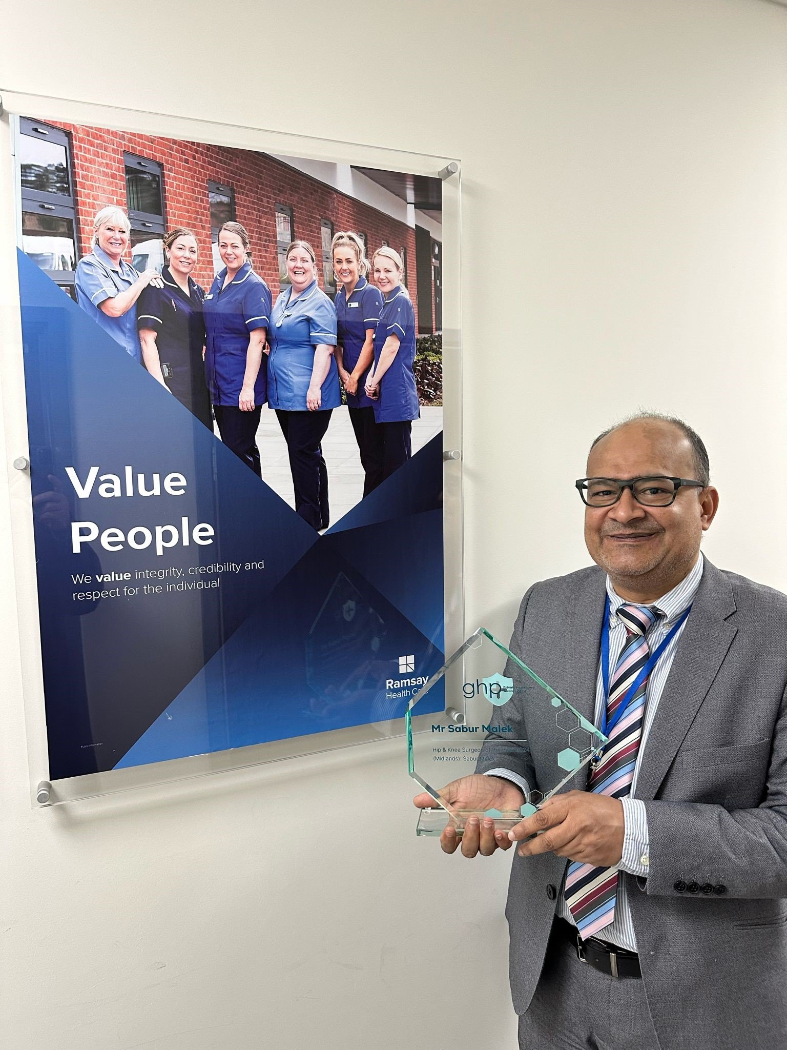 man stood holding a glass award smiling